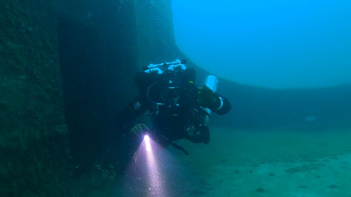 Diver descending a wreck wall with a dive light